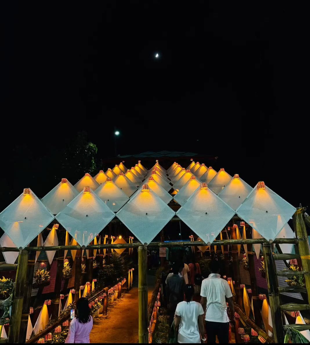 Frontal approach to the pyramid with diamond panels lit at night