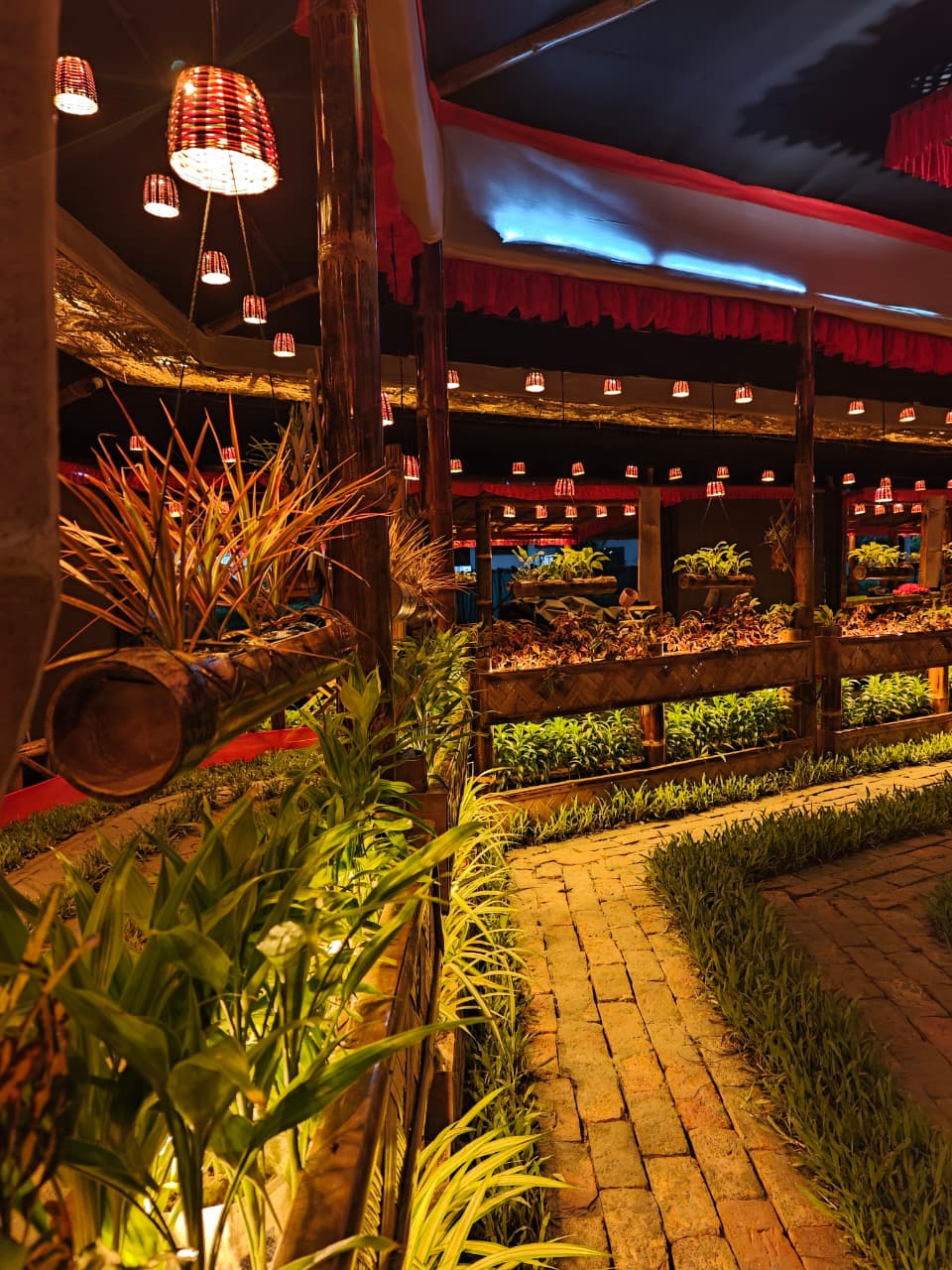 Interior garden pathway with plants and hanging lanterns lining the walkway