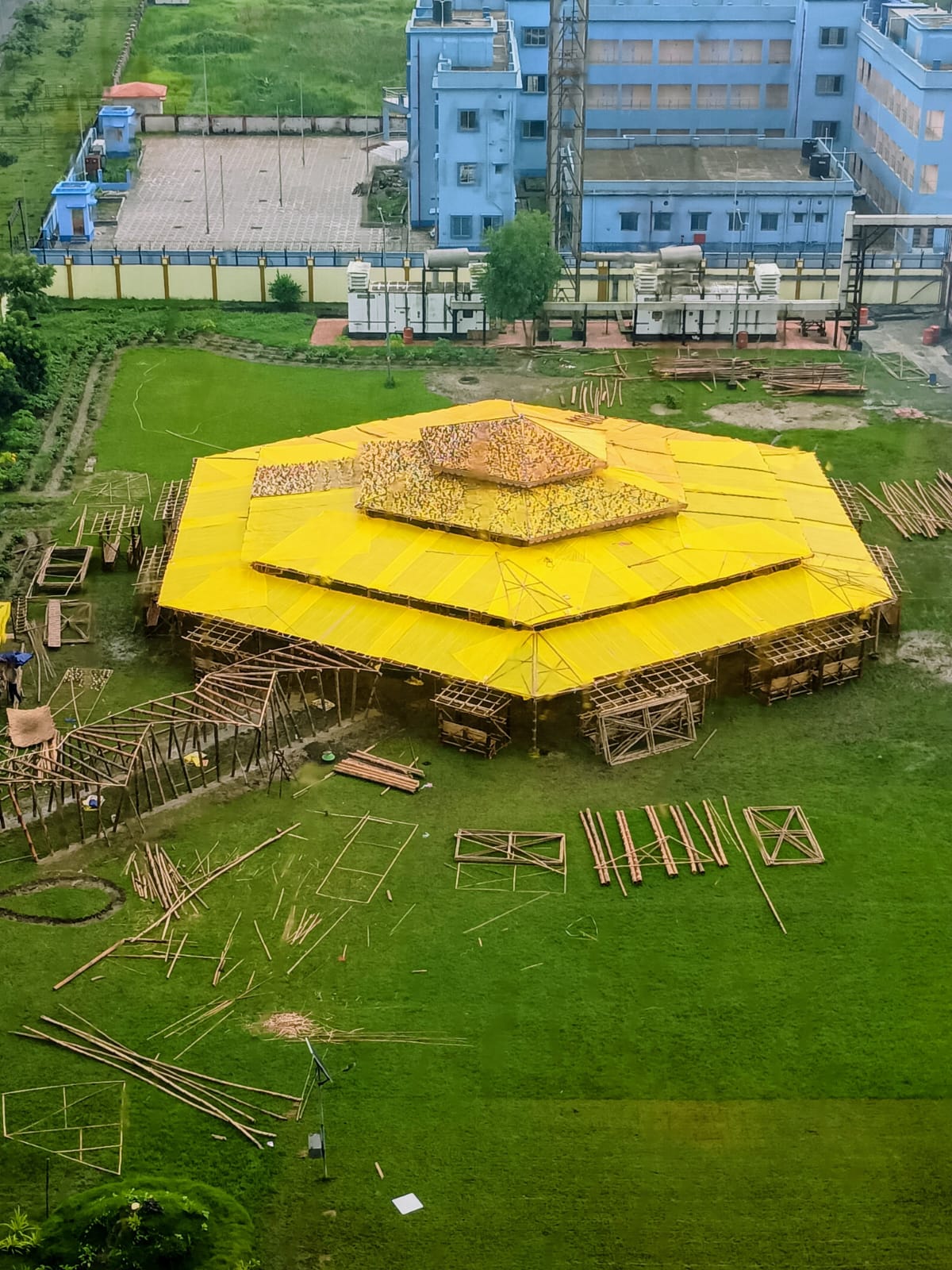 Aerial view showing yellow tarpaulin roof installed during mid-construction