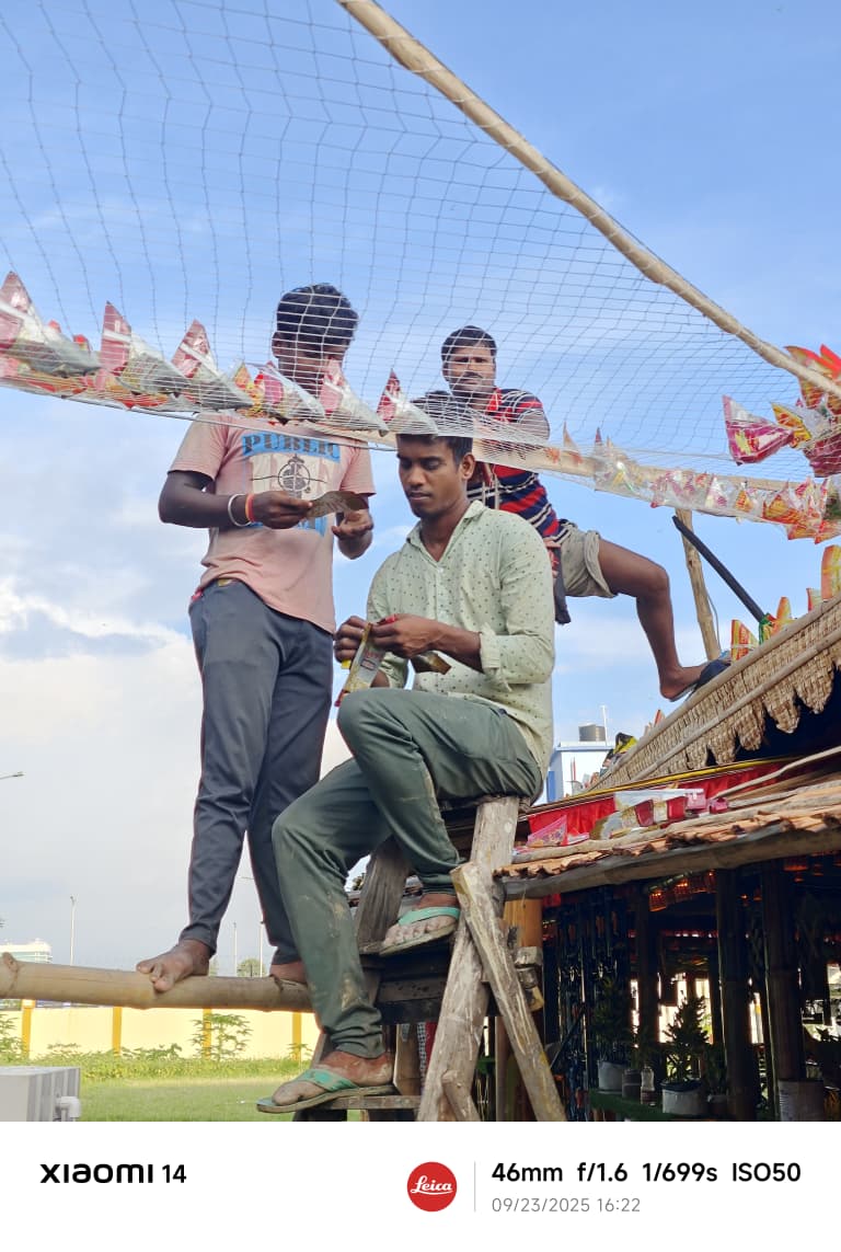 Karigars on rooftop installing decorative net and pinwheels