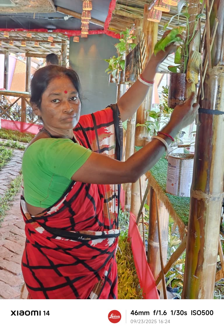 A woman karigar in red saree attaching plants to bamboo