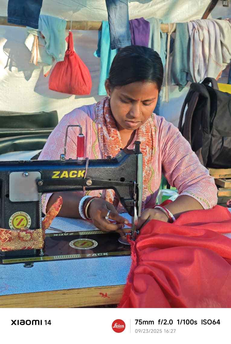 A woman karigar sewing red fabric on a sewing machine